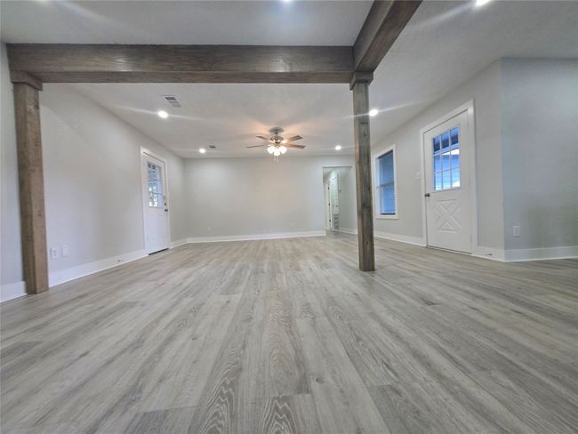 Unfurnished living room with beam ceiling, ceiling fan, light wood-type flooring, and recessed lighting | Image 10