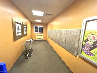 Hallway featuring a mail area, radiator heating unit, and a paneled ceiling | Image 3