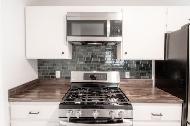 Kitchen featuring stainless steel appliances, butcher block countertops, white cabinetry, and backsplash | Image 14