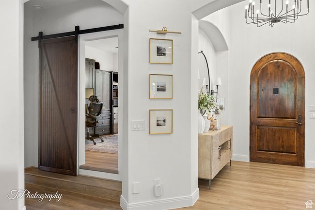 Entryway featuring wood finished floors, a chandelier, baseboards, and arched walkways | Image 12