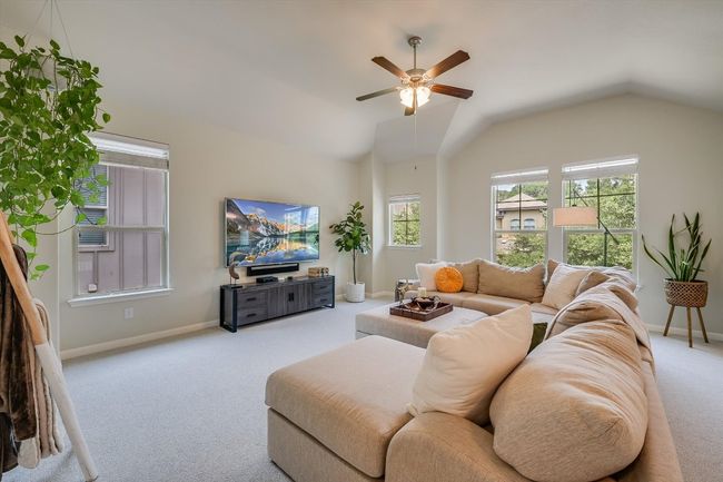 Carpeted living room featuring a ceiling fan, baseboards, and lofted ceiling | Image 19