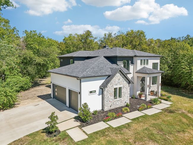 View of front of house featuring driveway, stone siding, an attached garage, stucco siding, and a front​​‌​​​​‌​​‌‌​‌‌​​​‌‌​​‌‌​‌​​​​​‌ lawn | Image 5