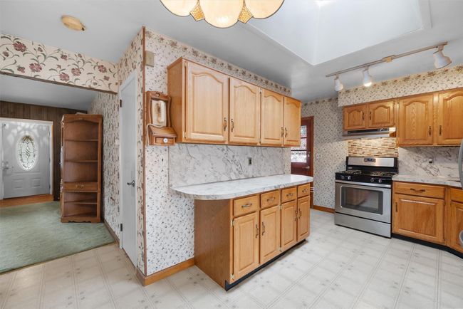 Kitchen with wallpapered walls, light countertops, stainless steel range with gas stovetop, and light floors | Image 12