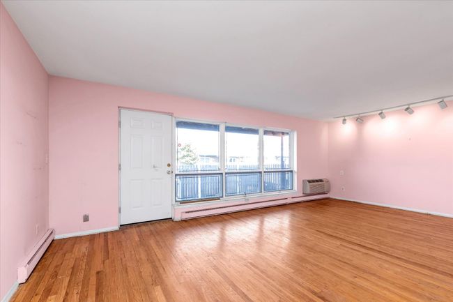 Light wood-style flooring, a baseboard heating unit, baseboards, and a wall mounted air conditioner | Image 7