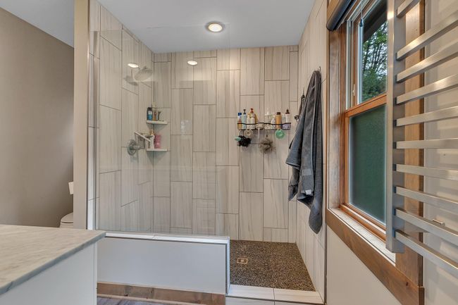 Spa-like bathroom includes a custom tile shower with modern design touches. | Image 21