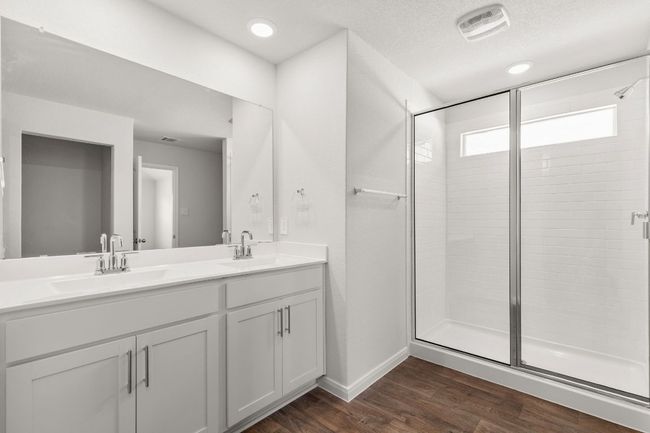 Bathroom with double vanity, a stall shower, wood finished floors, and baseboards | Image 10