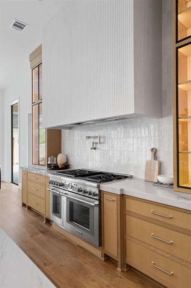 Your kitchen is adorned with a custom fluted, plaster hood range over a brand new Thermador gas range and pot filler. | Image 15