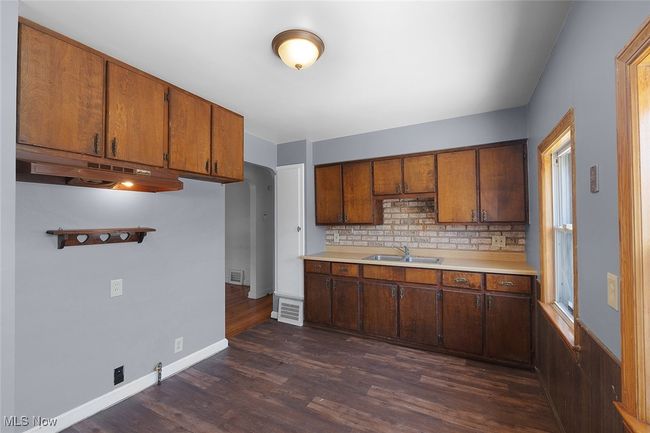 Kitchen with a sink, light countertops, dark wood-style floors, baseboards, and backsplash | Image 4