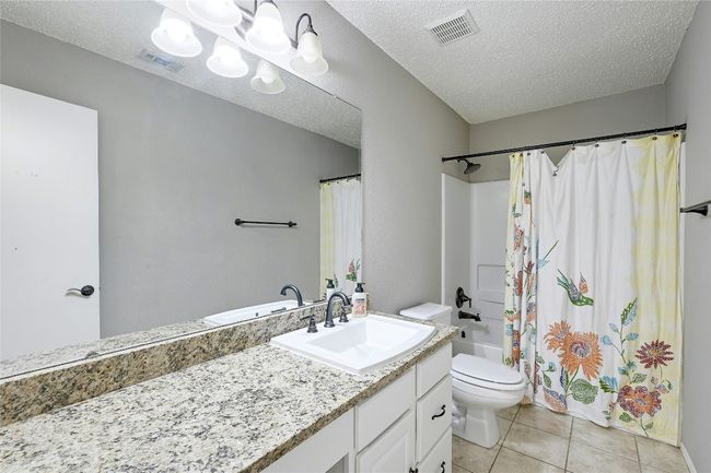 Bathroom featuring vanity, tile patterned floors, shower / bath combo, and a textured ceiling | Image 23