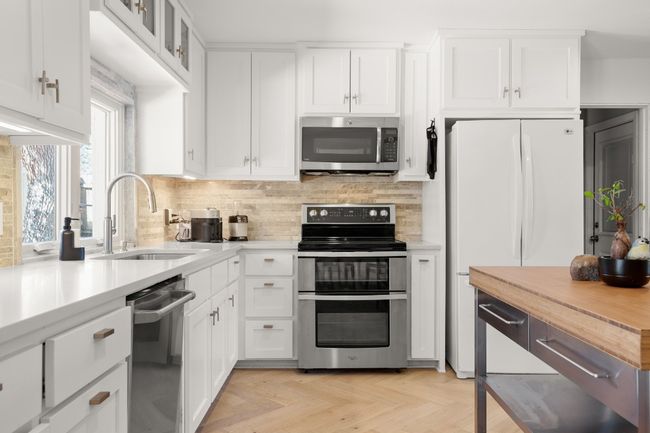 Kitchen with tasteful backsplash, appliances with stainless steel finishes, a sink, and white cabinets | Image 17
