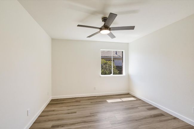 One of two secondary bedrooms with updated ceiling fan, luxury vinyl plank floor and fresh interior paint! | Image 17