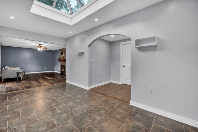 Unfurnished room with arched walkways, a skylight, recessed lighting, ceiling fan, and a fireplace | Image 15