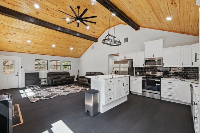 Kitchen with appliances with stainless steel finishes, wood ceiling, light countertops, and tasteful backsplash | Image 17