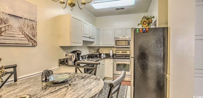 Kitchen with appliances with stainless steel finishes, white cabinetry, dark countertops, and wood finished floors | Image 10