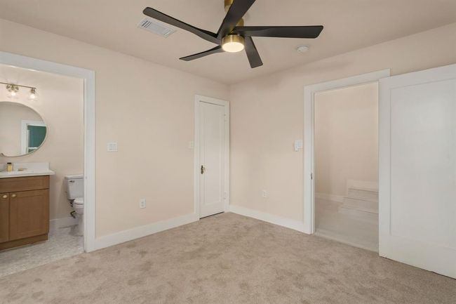 This spacious bedroom features plush carpeting, a high ceiling with a modern ceiling fan with light kit, and the added convenience of an en-suite bathroom, creating a comfortable and private retreat. | Image 32