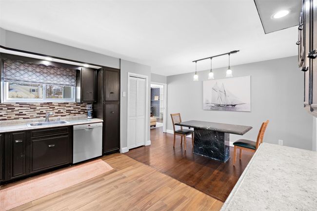 Kitchen with a sink, light countertops, stainless steel dishwasher, and decorative light fixtures | Image 16
