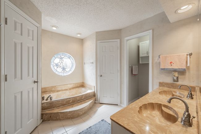 Bathroom with tile patterned flooring, a garden tub, double vanity, and a textured ceiling | Image 14