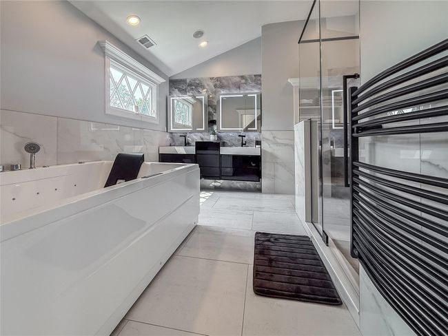 Full bathroom with double vanity, a jetted tub, vaulted ceiling, tile walls, and a shower stall | Image 22