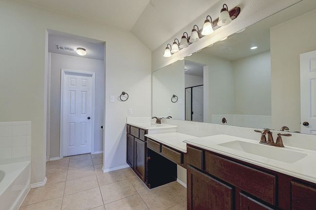 Bathroom with double vanity, tile patterned flooring, a garden tub, and baseboards | Image 12