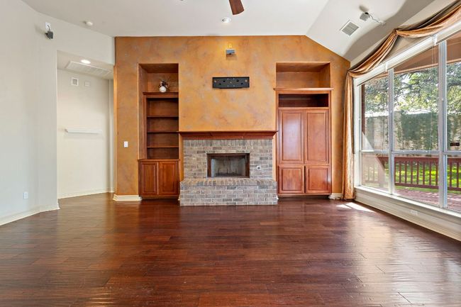 Unfurnished living room with visible vents, a ceiling fan, built in features, and dark wood finished floors | Image 6