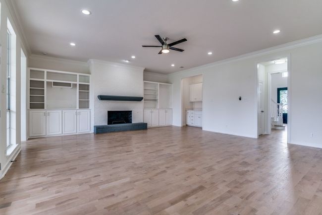 Unfurnished living room with a ceiling fan, a brick fireplace, light wood finished floors, recessed lighting, and crown molding | Image 7