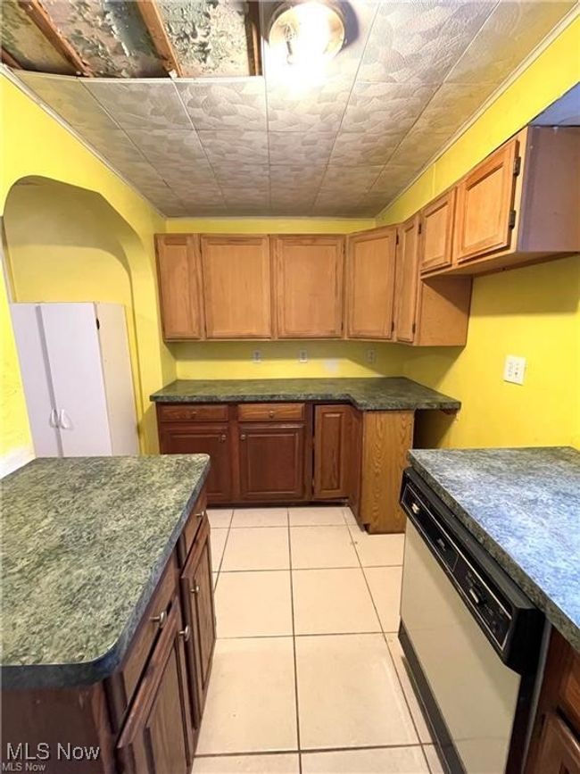 Kitchen with an ornate ceiling, dark countertops, dishwasher, and light tile patterned floors | Image 7