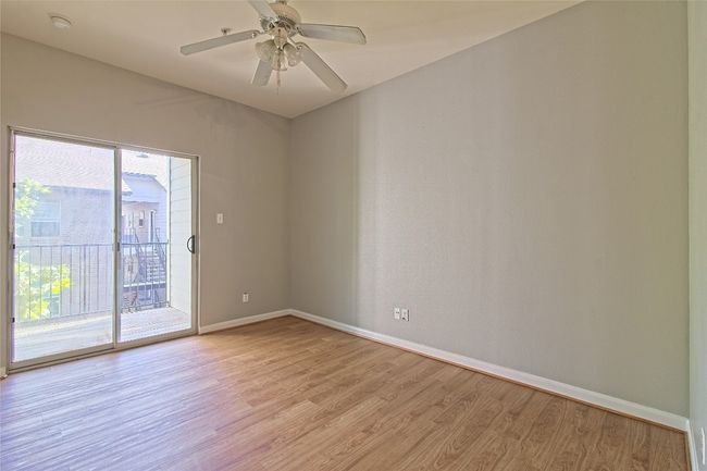 Empty room featuring light wood-type flooring, a smoke detector, and a ceiling fan | Image 28