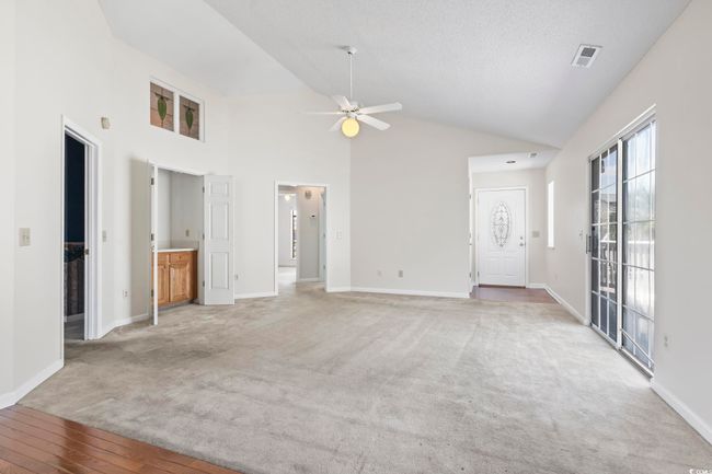 Unfurnished living room with ceiling fan, baseboards, light carpet, and high vaulted ceiling | Image 14
