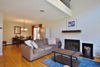 Living room with a glimpse of the loft above, dining room w/sliders to the deck | Image 3