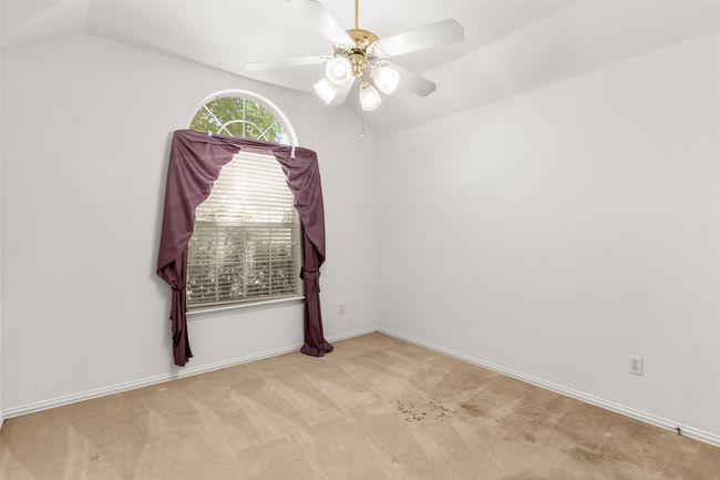 Carpeted empty room with lofted ceiling, a ceiling fan, and baseboards | Image 35