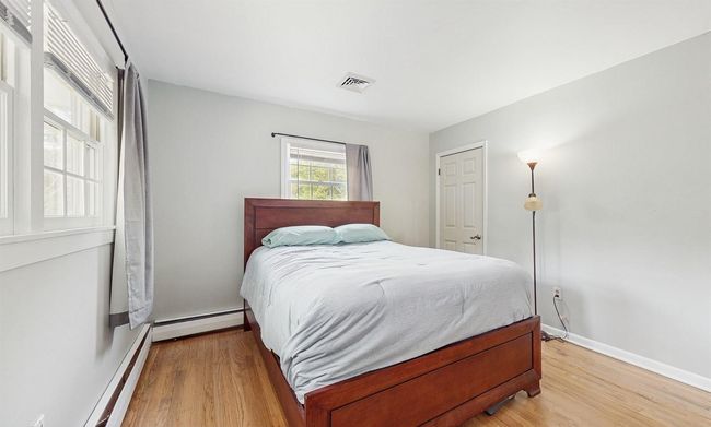Bedroom with a baseboard heating, light wood finished floors. | Image 21