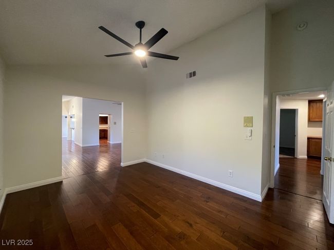 Spare room featuring high vaulted ceiling, a ceiling fan, and dark wood-type flooring | Image 12