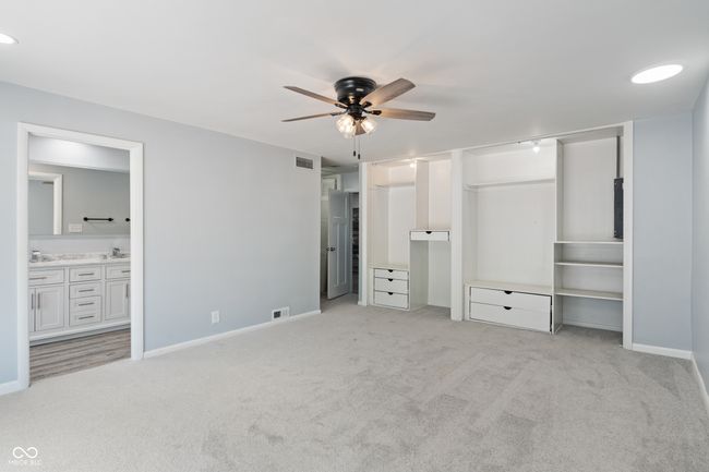 unfurnished bedroom with light colored carpet, baseboards, connected bathroom, and a ceiling fan | Image 18