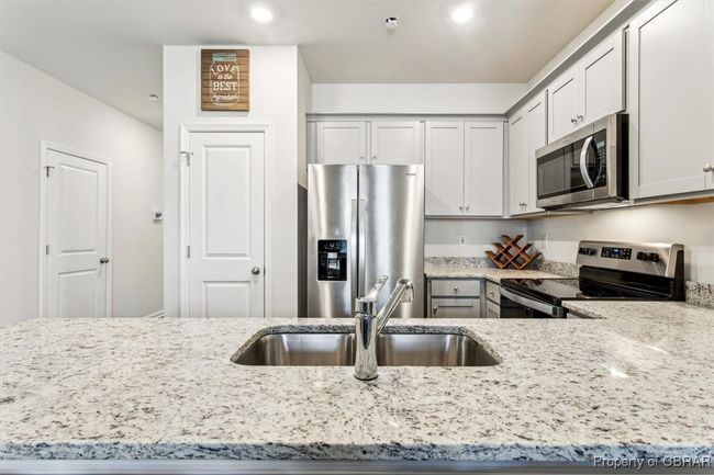 Kitchen with light stone countertops, stainless steel appliances, a sink, and recessed lighting | Image 4