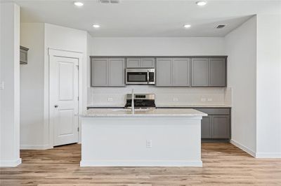 Kitchen with appliances with stainless steel finishes, light hardwood / wood-style flooring, a kitchen island with sink, and decorative backsplash | Image 2