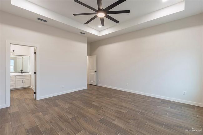 Empty room with ceiling fan and a raised ceiling | Image 13