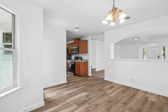 Unfurnished living room featuring baseboards, light wood-style flooring, a notable chandelier, and a healthy amount of sunlight | Image 11