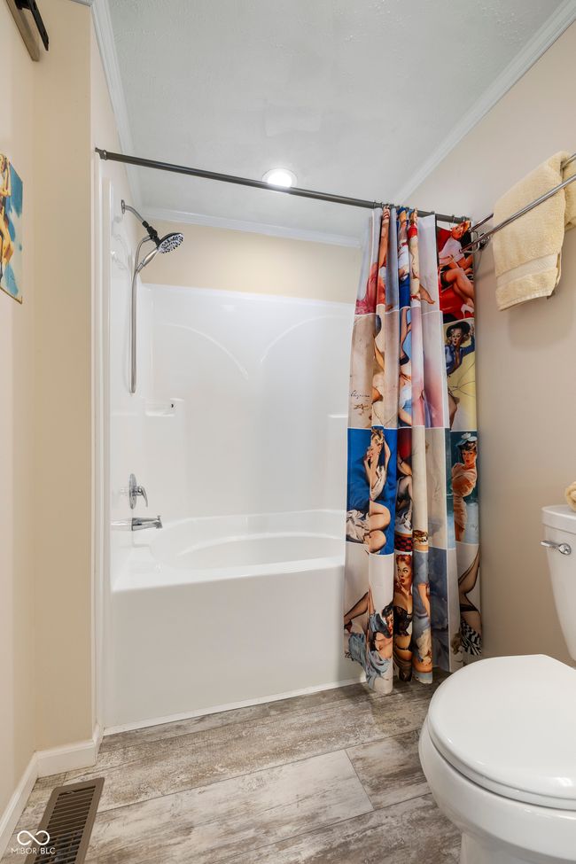 full bath with ornamental molding, toilet, shower / bathtub combination with curtain, and wood finished floors | Image 26