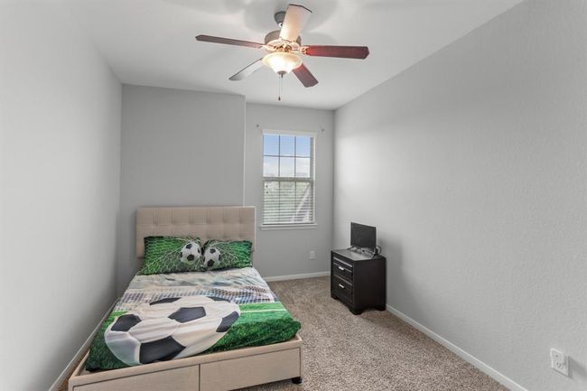 Wonderfully appointed secondary bedroom, featuring neutral paint, plush carpet, a window with privacy blinds, and a ceiling fan. | Image 15