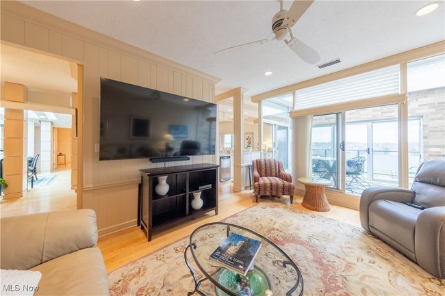 Den with a ceiling fan, visible vents, light wood-style flooring, a decorative wall, and ornate columns | Image 25