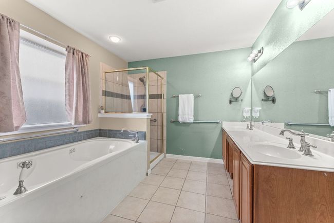 Bathroom featuring a sink, tile patterned flooring, a stall shower, and a bath | Image 19