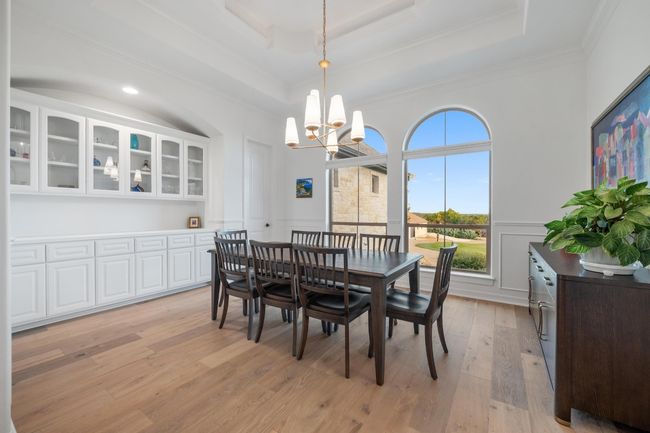 Dining room with a chandelier, crown molding, light wood-type flooring, wainscoting, and a tray ceiling | Image 12