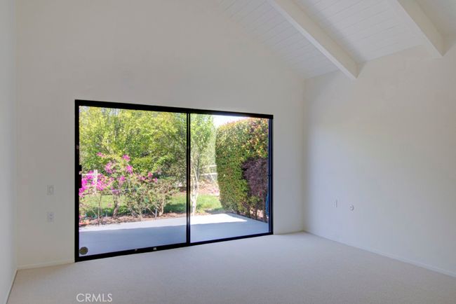 Primary bedroom has a vaulted ceiling and direct access to the rear patio. | Image 18