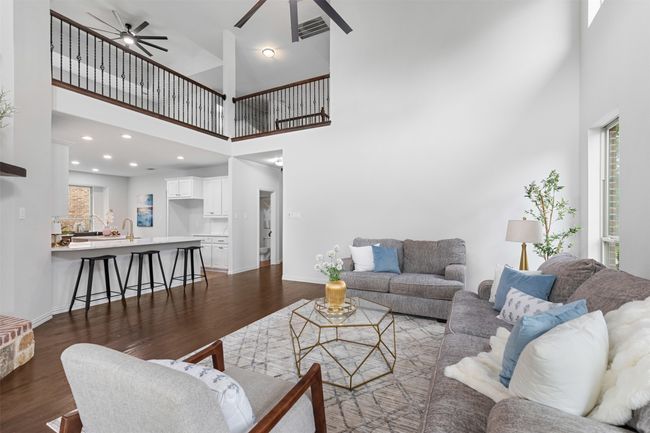 Living area with a towering ceiling, visible vents, a ceiling fan, and dark wood-style floors | Image 13