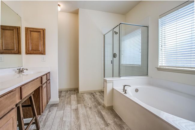 Primary en-suite bathroom featuring double vanity, medicine cabinet, garden tub, separate shower & LV flooring. | Image 21