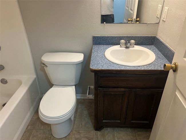 Bathroom with a textured wall, vanity, and shower / bathtub combination | Image 13
