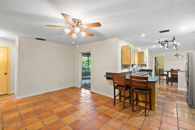 Kitchen featuring stainless steel refrigerator, sink, tile patterned floors, a kitchen breakfast bar, and ceiling fan | Image 13