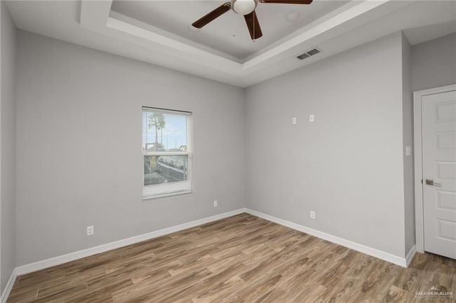 Spare room with a tray ceiling, baseboards, visible vents, and light wood finished floors | Image 6
