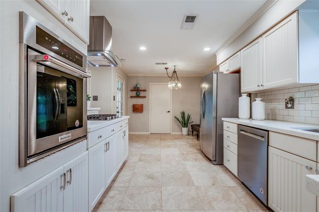 Spacious kitchen with white cabinets, white subway tiled back splash, travertine tiled floor, Kitchen Aid Gas cook top & Kitchen Aid single Oven, vent, refrigerator included in the sales price, recessed lighting, through to breakfast room | Image 17