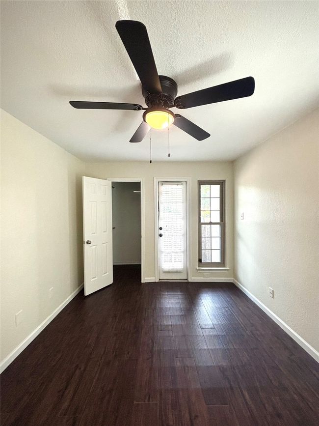 Bedroom with private patio, walk in closet, and dark wood finished floors | Image 14
